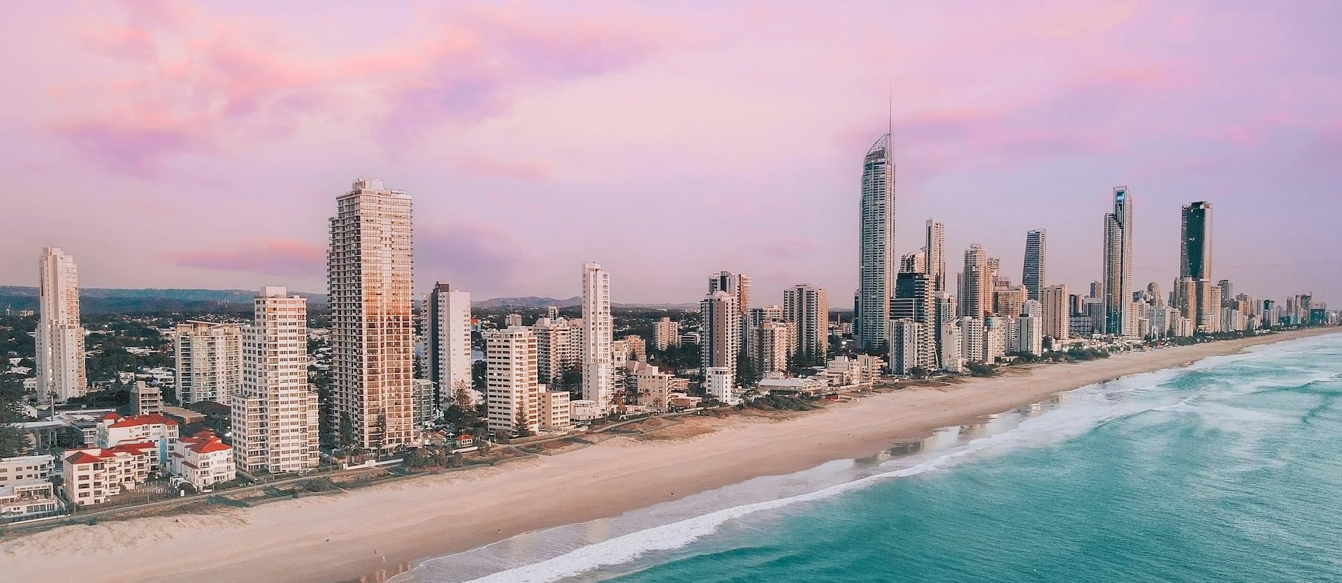 An aerial shot of the Gold Coast, featuring the skyline with a purple sky in the background.